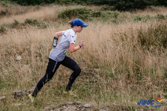 Image of athlete wearing NZ uniform running through a grass field