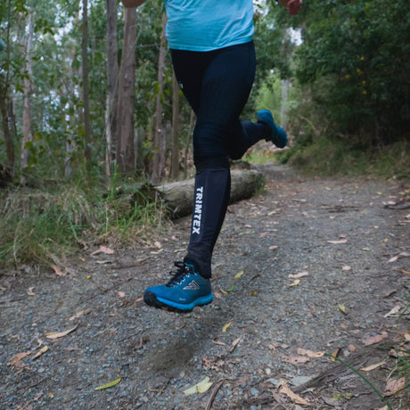 A runner on a forest trail wearing black trimtex gaiters and blue VJ Falcon shoes