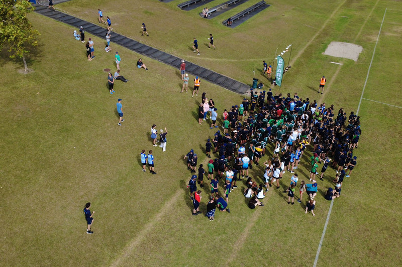 Aerial view of hundreds of school students gathered on a field at an Auckland Schools Sprint Series event