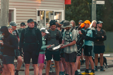 Adventure racers with packs gathered at a race start in the early morning