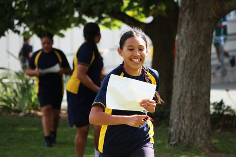 A secondary school orienteer running with a map at an Auckland Schools Sprint Series event